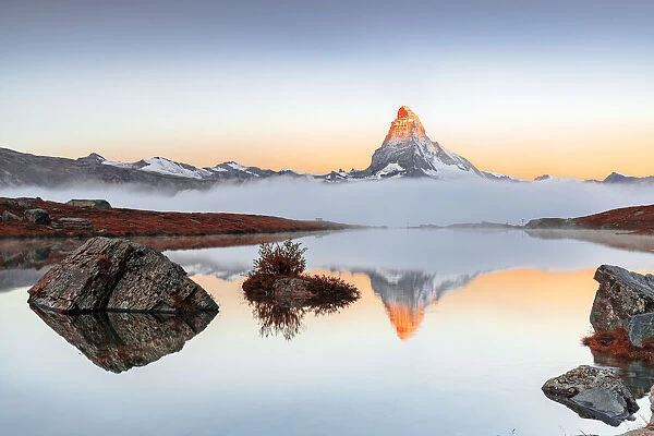 Autumn fog over Matterhorn reflected in the clear water of Stellisee lake at dawn