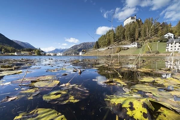 Autumn leaves in Lake Tarasp frame the old castle, Inn district, Canton of Graubunden