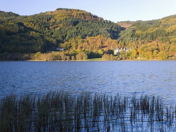 Autumn view across Loch Achray to wooded hills, the former Trossachs Hotel visible
