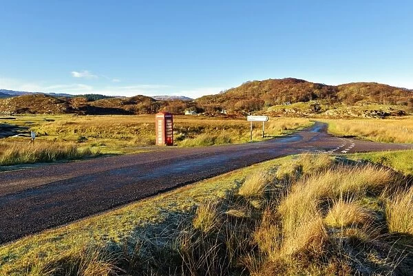 An autumn view of a red telephone box at the side of a quiet road in the remote Ardnamurchan