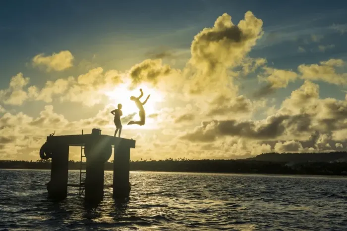 Framed Print : Backlit local boys jumping into the water of the lagoon of Wallis from a platform Framed Print : Backlit local boys jumping into the water of the lagoon of Wallis from a platform