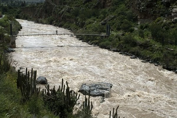 Backpacker crosses bridge over Urubamba River, on the Inca Trail, Peru, South America