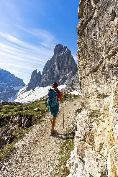 Backpacker woman with hiking poles enjoying the view to Croda Dei Toni from path