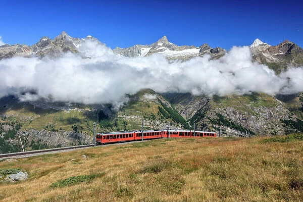 The Bahn train on its route with high peaks and mountain range in the background