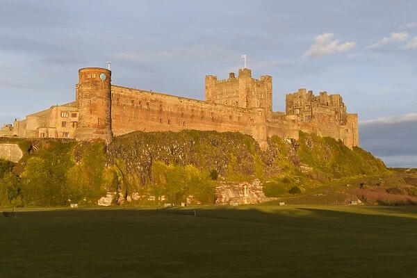 Bamburgh Castle and Cricket Green in evening sunshine, Bamburgh, Northumberland, England, United Kingdom, Europe