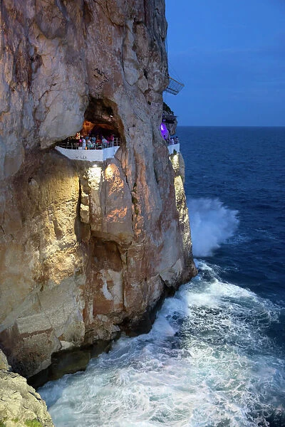 Bar built in cliff caves, Cova d en Xoroi in evening, Cala en Porter, Menorca, Balearic Islands