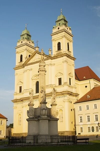 Baroque Church of the Assumption of the Virgin Mary and Baroque plague column at sunset