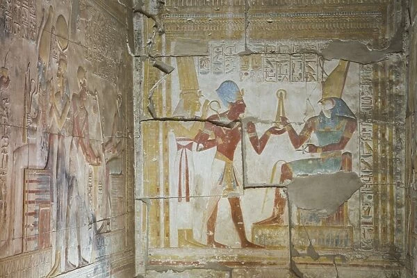 Bas relief of Pharaoh Seti I making an offering to the seated God Horus on right