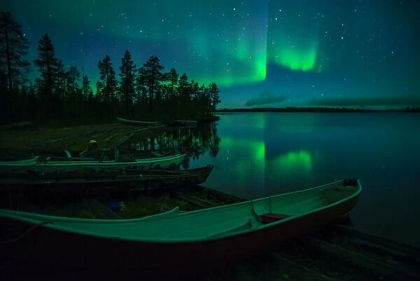 Beached canoes and Aurora Borealis and stars reflected in lake at night, Muonio, Lapland
