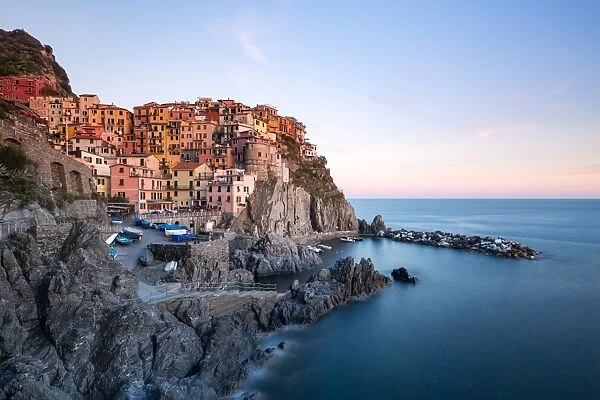 Beautiful sunset light shines on the colourful town of Manarola during a long exposure
