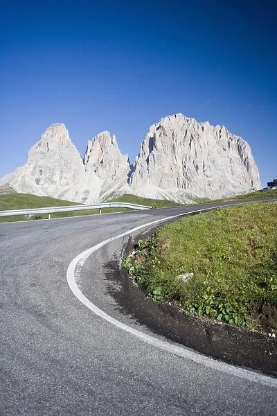 A bend in a road passing the craggy peaks of the Sassolungo in the Dolomites