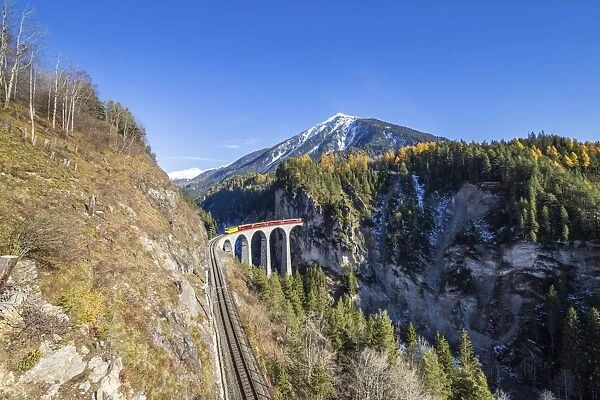 Bernina Express passes over the Landwasser Viadukt surrounded by colorful woods