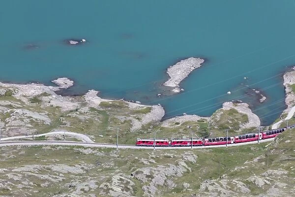 The Bernina Express train passes on the shores of Lago Bianco, Bernina Pass, Canton of Graubunden