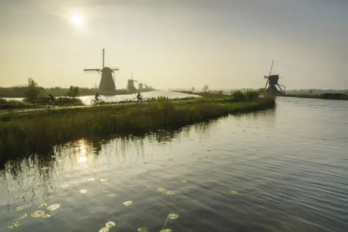 Framed Print : Bicycles run through a path between the canal and windmills, Kinderdijk, Rotterdam