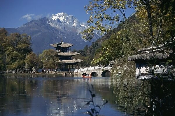 Black Dragon Pool park with bridge and pagoda, and mountains in the background at Lijiang