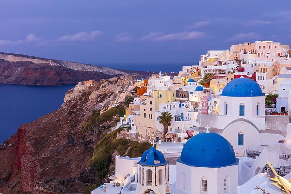 Blue domed white church and colourful buildings at sunrise, Oia, Santorini, Cyclades, Greek Islands, Greece, Europe