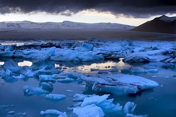 Blue icebergs floating on the Jokulsarlon glacial lagoon at sunset, South Iceland