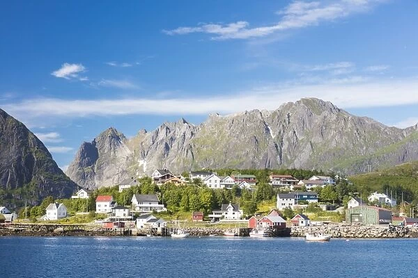 The blue sea frames the fishing village and the rocky peaks, Reine, Moskenesoya, Lofoten Islands