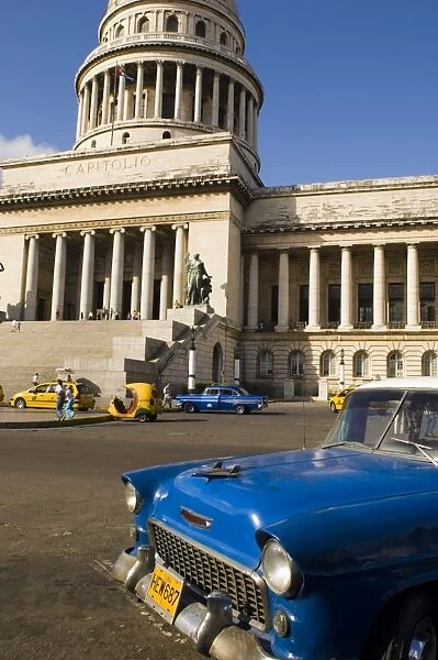 A blue vintage 1950s American Chevy in front of the Capitolio in central Havana