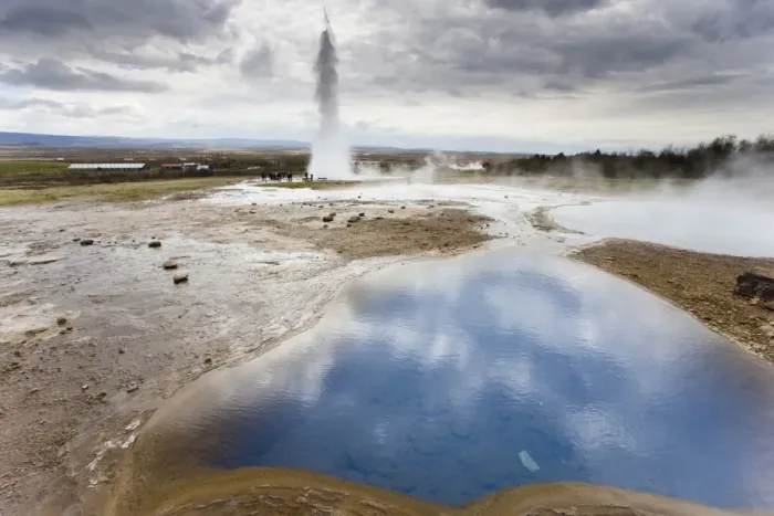 Framed Print : Blue water in geothermal pool with water spout from Strokkur Geysir visible in the distance