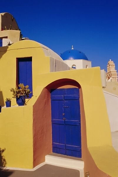 Blue and yellow traditional house with churches in the background
