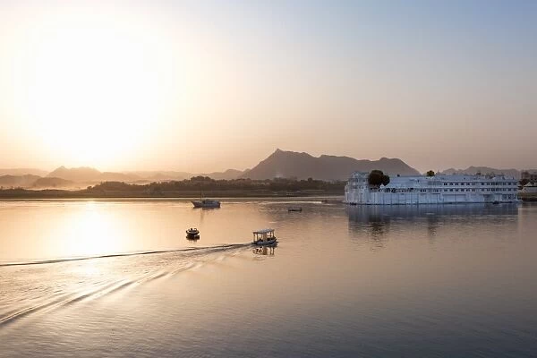 Boat going out to Lake Palace Hotel at dusk, the hotel is situated in the middle of Lake Pichola
