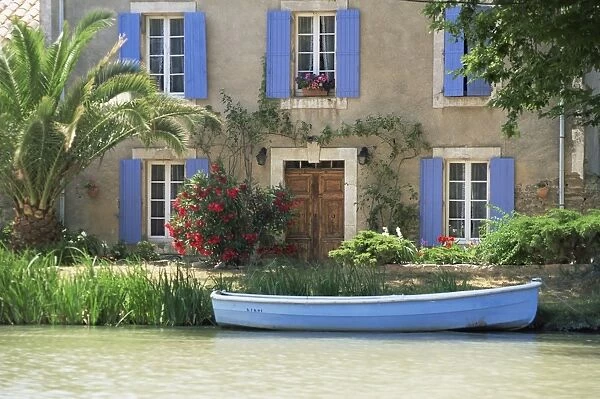 Boat moored alongside house on the bank of the Canal du Midi, Le Somail