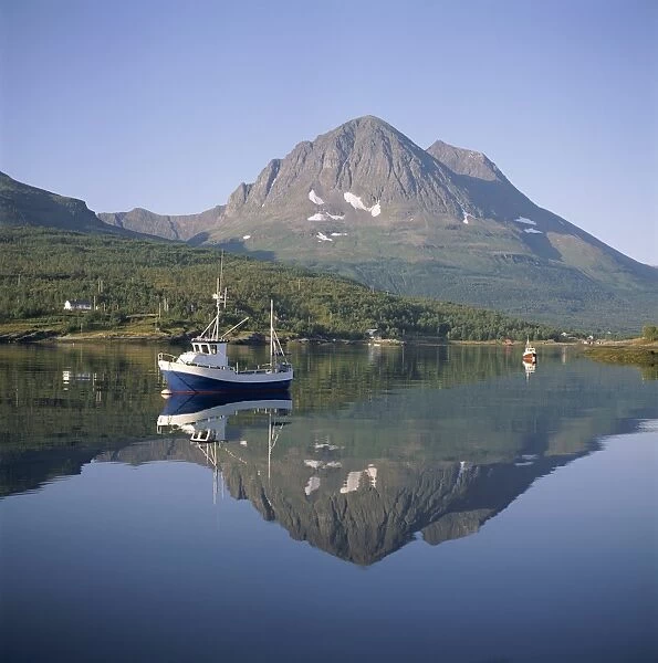 Boat and mountains reflected in tranquil water