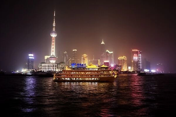 Boat set against Shanghai illuminated skyline, Shanghai, China, Asia