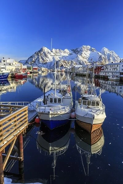 Boats docked in the calm waters of the port of Henningsvaer with the Norwegian Alps in the background, Lofoten Islands, Arctic, Norway, Scandinavia, Europe