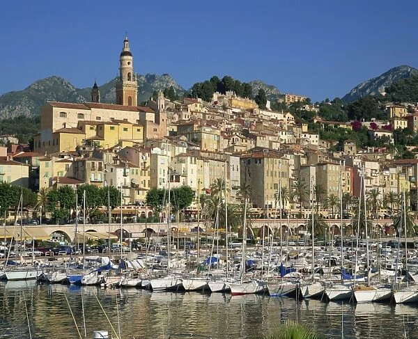 Boats in the harbour with the houses and church of the town of Menton behind