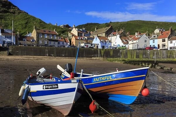 Boats at low tide, cliffs, steep cove of coastal fishing village in summer, Staithes