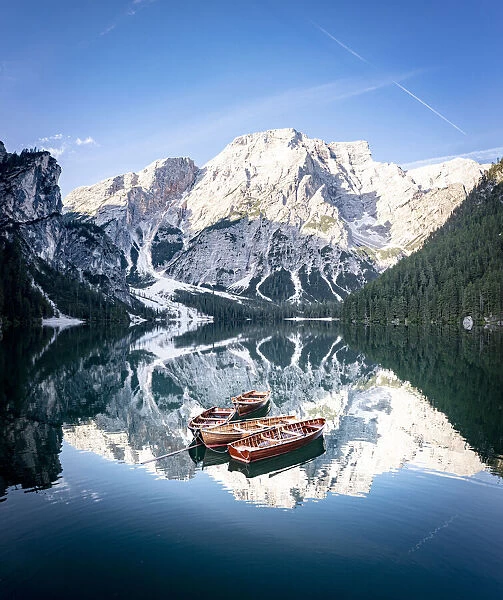 Boats moored in Lake Braies (Pragser Wildsee) with mountains reflected in water at