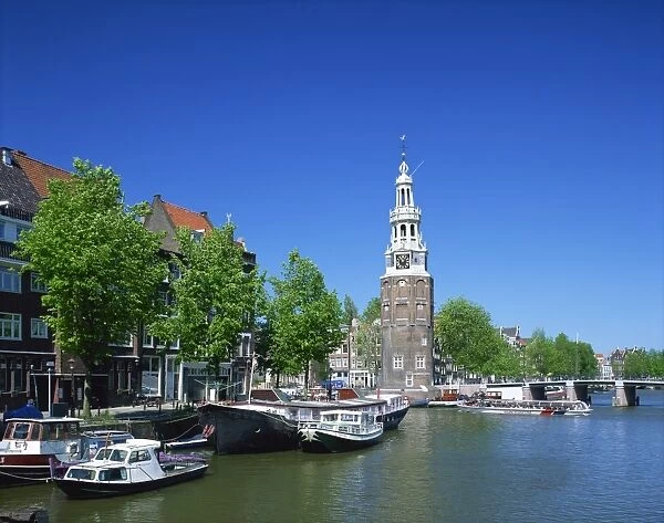 Boats on the Ovde Schans Canal with the Montelbaanstoren tower behind, in Amsterdam