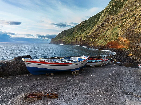 Some boats on a pier below a cliff in Sao Miguel Island in the Azores, Portugal, Atlantic, Europe