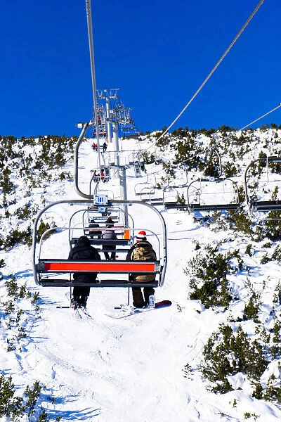 Borovets Ski Resort, a skier and snowboarder sit on Markudjik ski lift, Bulgaria, Europe