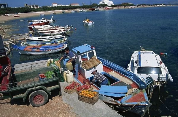 Boxes of tomatoes and oranges on quay as supply boat