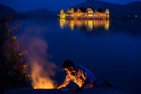 Boy cooking at twilight by the Jal Mahal Floating Lake Palace, Jaipur, Rajasthan