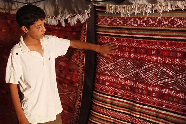 Boy showing a rug in a carpet shop, Toujane, Tunisia, North Africa, Africa