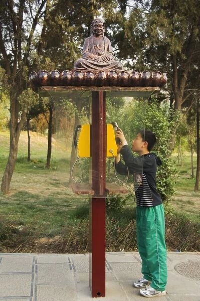 A boy using a monk decorated telephone box at Shaolin temple, birthplace of Kung Fu martial arts