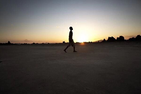 A boy walks through the desolate landscape of Lac Abbe, Djibouti, Africa