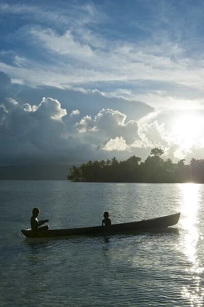 Boys in a canoe in backlit in the Marovo Lagoon, Solomon Islands, Pacific
