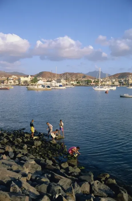 Framed Print : Boys on the rocks, with the harbour and town in the background, at Mindelo Framed Print : Boys on the rocks, with the harbour and town in the background, at Mindelo