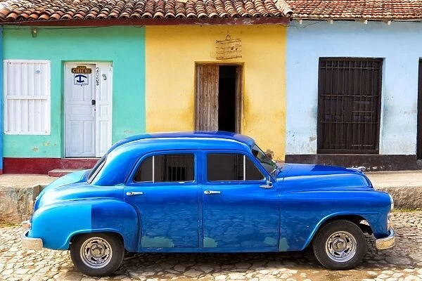 Bright blue vintage American car parked in front of colourful painted colonial houses, Trinidad, UNESCO World Heritage Site, Cuba, West Indies, Central America