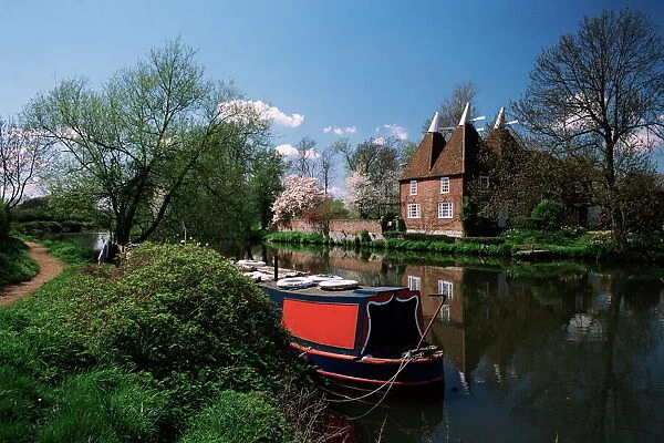 Brightly painted barge and oast houses on the River Medway, Yalding, near Maidstone