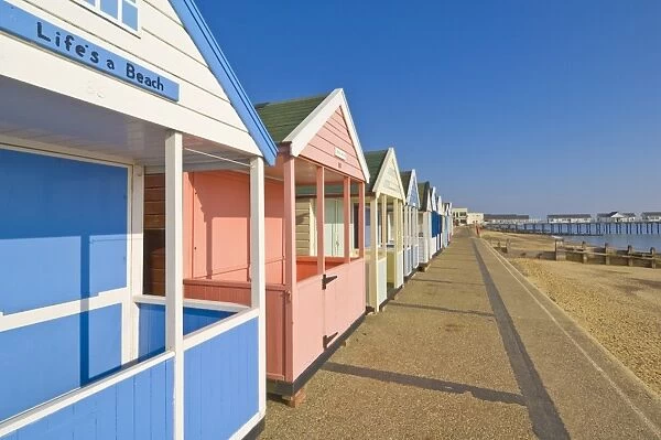 Brightly painted beach huts in the afternoon sunshine, on the seafront promenade