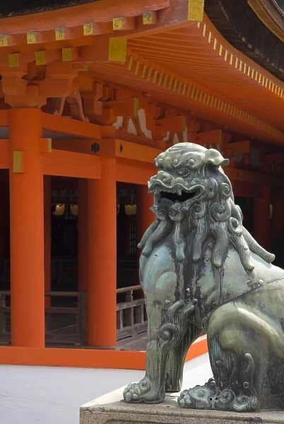 Bronze lion with traditional orange wooden roof beyond