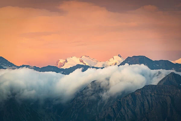 Burning sky at sunrise over the snow capped Monte Rosa surrounded by a sea of clouds