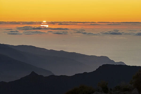 Burning sky at sunset over the Atlantic Ocean and silhouettes of mountains from Pico
