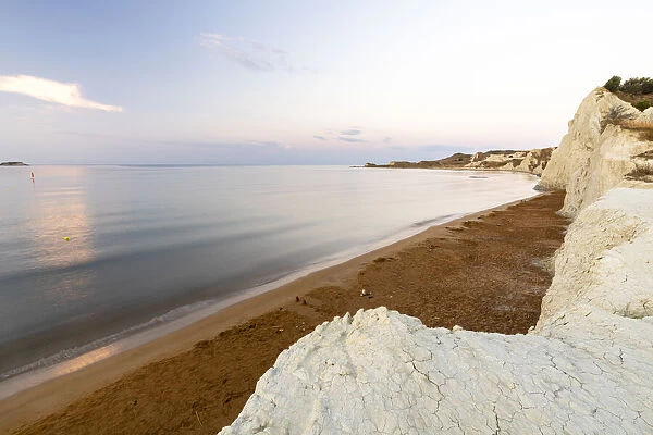 Calm sea at dawn framed by limestone cliffs overlooking the gold sand of Xi beach, Kefalonia, Ionian Islands, Greek Islands, Greece, Europe